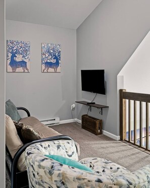 A room with a bed, a TV mounted on a wall, and two wall-mounted paintings. - Lake Front Cabin with Hot Tub and Dock (Pocono Lake)
