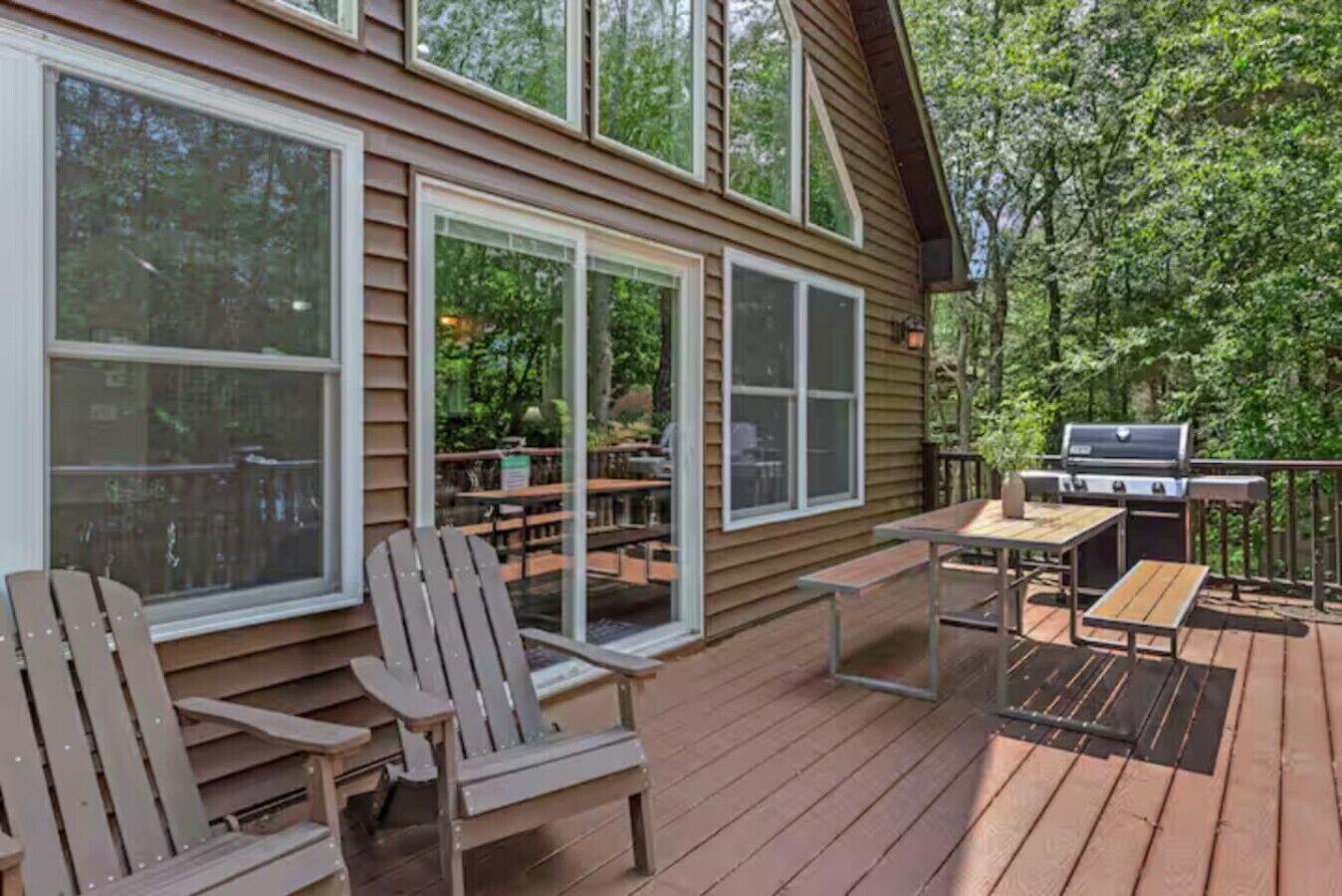 A wooden deck with outdoor furniture, including chairs and a table, and a grill.