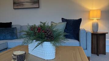 A living room with a sofa, a coffee table with a decorative plant, a lamp, and two paintings on the wall.