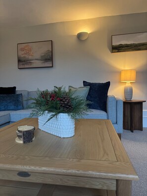 Un salon comprenant un canapé, une table basse ornée d’une plante décorative, une lampe et deux tableaux accrochés au mur.
