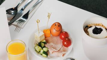 A white table with a plate of food, a glass of orange juice, a salt shaker, and a bowl of yogurt with berries.