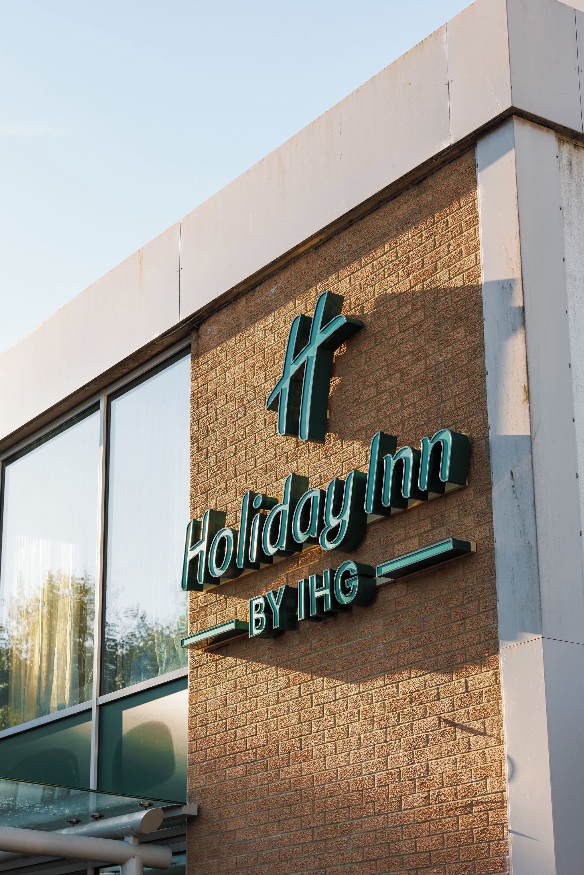 A Holiday Inn sign on a brick building with large windows.