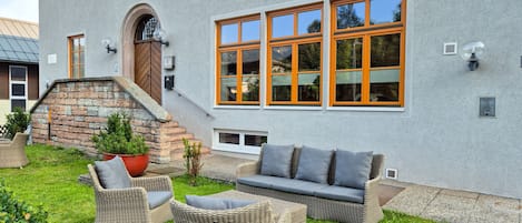 A modern building with large windows, a stone staircase, and outdoor wicker furniture.