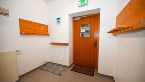 A hallway with a wooden door, a radiator, a metal rack, and a welcome mat. - Schmitten 27 - Room 4 200m From ski Lift (Zell am See)