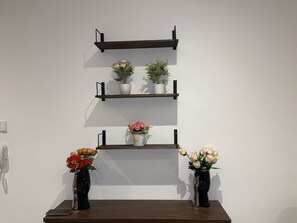 Eine an der Wand befestigte Regalreihe mit drei Ebenen, auf denen jeweils eine Blumentopf-Pflanze steht.