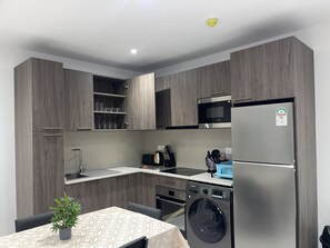 Eine moderne Küche mit grauen Schränken, einem Edelstahl-Kühlschrank, einer Mikrowelle und einem Einbauofen.