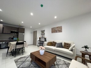 Ein modernes Wohnzimmer mit einer Couch, einem Couchtisch und einem Essbereich mit Stühlen und einem Tisch.