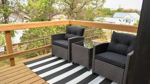 Ein Balkon mit Korbmöbeln und einer Streifenoptik-Isolierung.