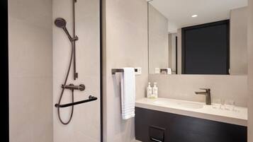 A modern bathroom with a glass-enclosed shower, a large mirror, and a vanity with a sink and towel rack.