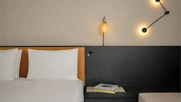 A hotel room with a bed, bedside table, and a wall-mounted lamp.