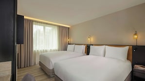 Habitación de hotel con dos camas, televisión, escritorio y una silla.