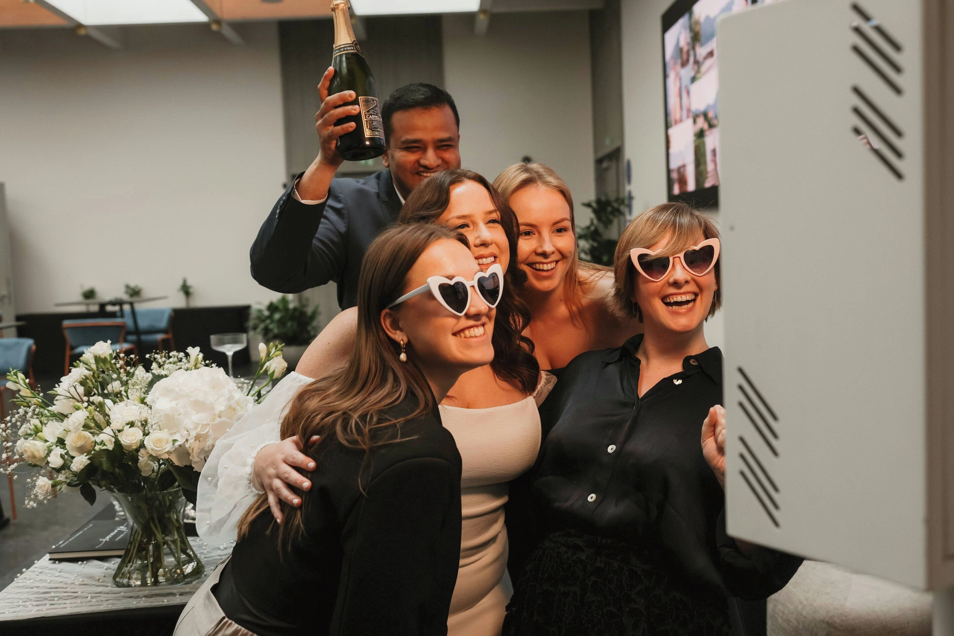 A group of people taking a selfie with a bottle of champagne.