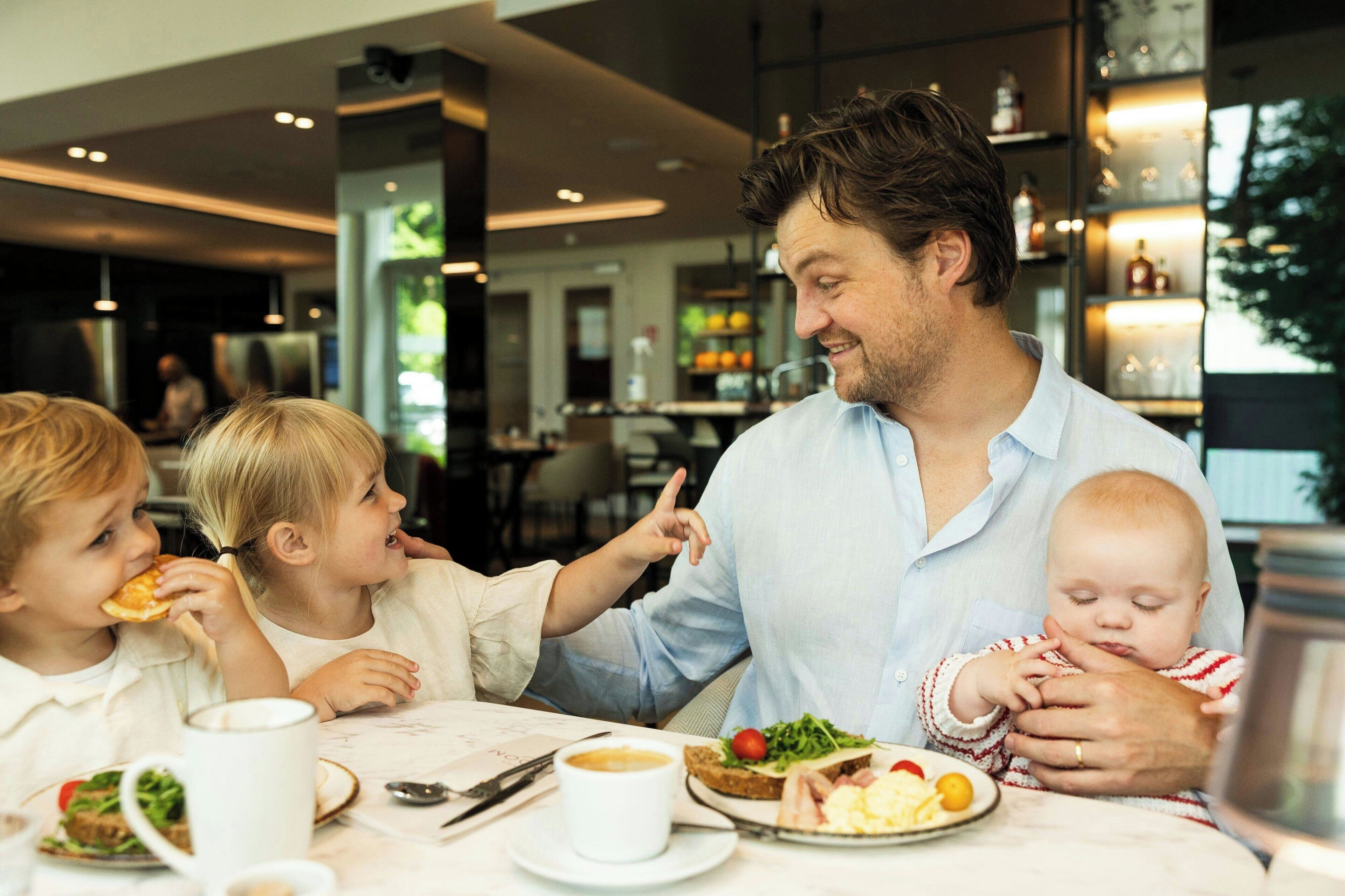 Una familia cenando en un restaurante con una decoración moderna, incluyendo una zona de bar al fondo.