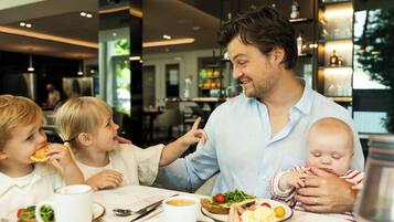 Una familia cenando en un restaurante con una decoración moderna, incluyendo una zona de bar al fondo.
