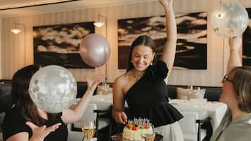 Eine Gruppe von Personen feiert einen Geburtstag mit einer Torte und Luftballons in einem Restaurant.