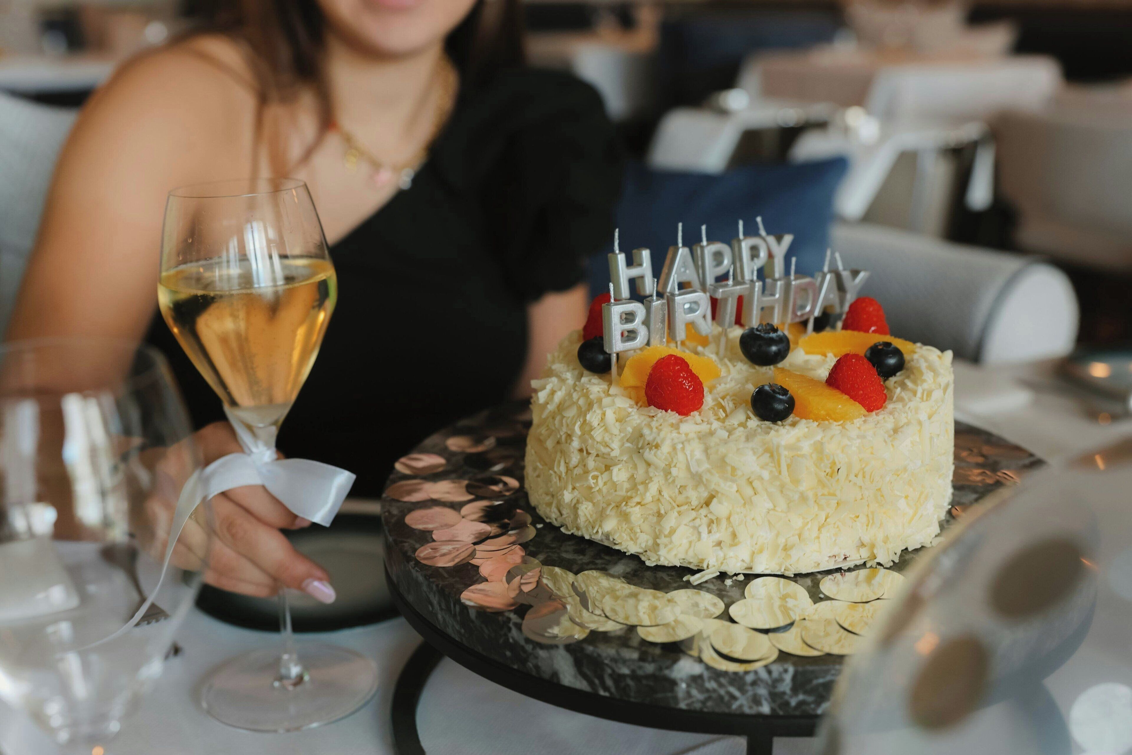 A birthday cake with 'Happy Birthday' candles on a marble table.