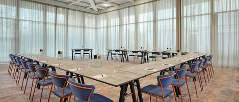 A conference room with a long table, blue chairs, and large windows.