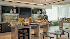 Una barra de desayuno moderna con diversas opciones de alimentos, como frutas, pasteles y bebidas.