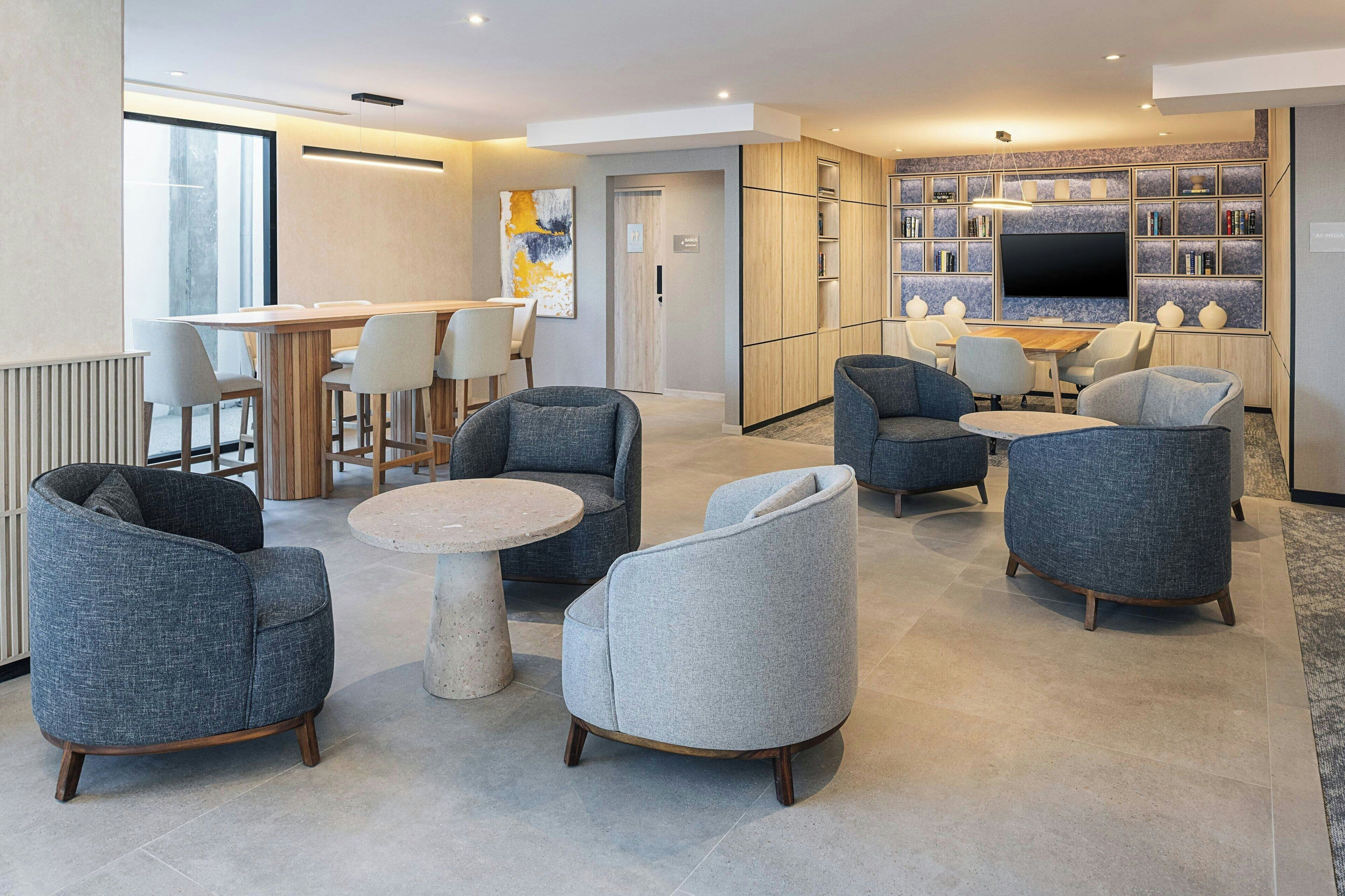 Una sala moderna con sofás, una mesa de centro y una zona de televisión con estanterías.