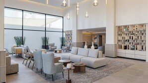 A spacious living area with a large sofa, armchairs, a coffee table, and a bookshelf. - AC Hotel By Marriott San Luis Potosi (San Luis Potosi)