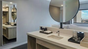 A modern hotel bathroom with a large mirror, a sink, and a vanity area.