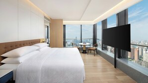 A modern hotel room with a large bed, a TV, a balcony with a city view, and a small table with chairs. - Four Points By Sheraton Wuhan Hankou (Wuhan)