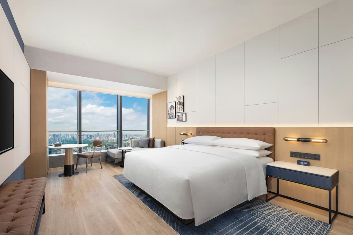 Une chambre d’hôtel moderne dotée d’un grand lit, d’un bureau, d’une chaise et offrant une vue sur la ville.