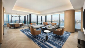 A spacious living area with a large sofa, coffee table, and dining set. It features large windows offering a city view. - Four Points By Sheraton Wuhan Hankou (Wuhan)