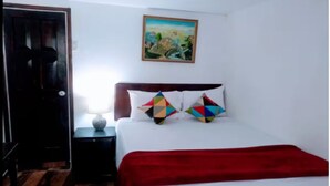 A bedroom with a bed, a nightstand, a red blanket, and a painting on the wall.