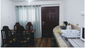 A small, compact kitchen with a dining table, chairs, a microwave, and a sink.