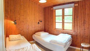 A room with wooden walls, a large window, two beds, and two wall-mounted lamps. - Perfect holiday home for large families (Aakirkeby)