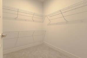 A corner closet with metal wire shelves, a door, and a carpeted floor.