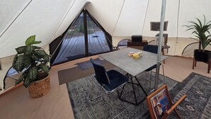 Une tente comprenant un espace repas, avec une table, des chaises et un tapis.