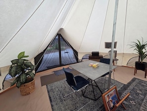 Une tente comprenant un espace repas, avec une table, des chaises et un tapis.