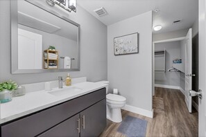 Une salle de bain moderne avec un lavabo blanc, des meubles sombres, des toilettes et un espace douche.