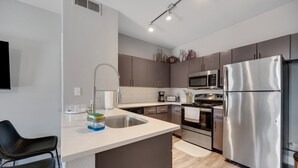 A modern kitchen with stainless steel appliances, a built-in microwave, and a large island with a sink. - Central Relaxing 1br Phoenix Retreat Near Airport 1 Bedroom Apts (Phoenix)