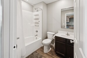 A bathroom with a bathtub, toilet, and vanity. - Rustic-industrial Loft With Courthouse Views 3 Bedroom Apts (Bloomington)