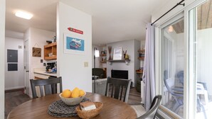 A dining area with a round table, chairs, a bowl of fruit, and a sign indicating ski rental. - Glades 14 1 Bedroom Condo (Warren)