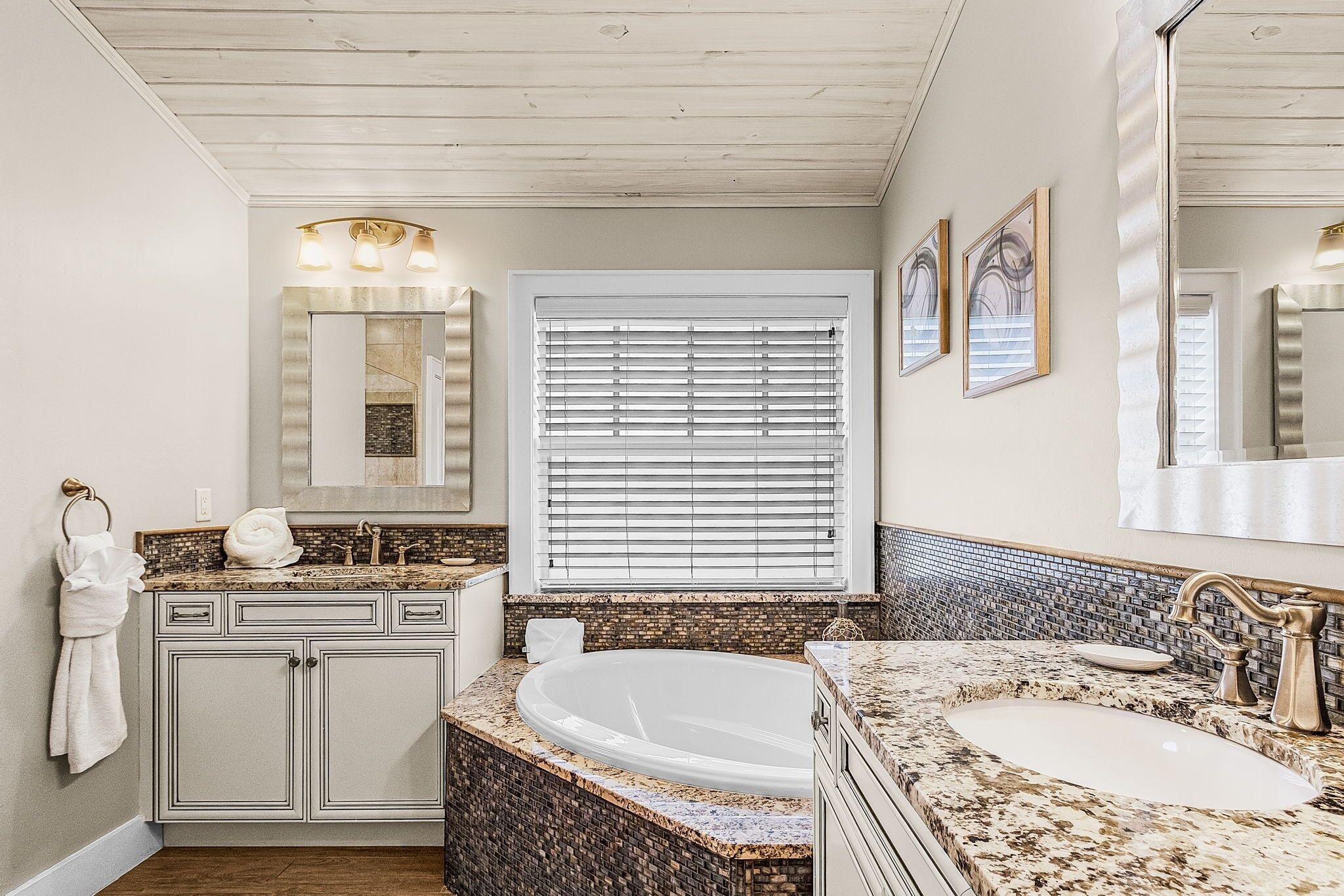 A bathroom with a freestanding bathtub, a vanity with a sink, and a large mirror.