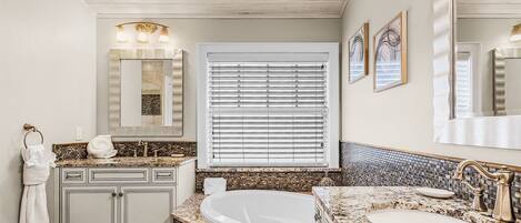 A bathroom with a freestanding bathtub, a vanity with a sink, and a large mirror.