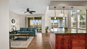 A modern kitchen with wooden cabinets, a central island, and pendant lighting. - Kauai Pili Mai 14i 3 Bedroom Condo (Koloa)