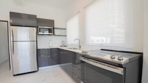 A modern kitchen with stainless steel appliances, a built-in oven, and a large window providing natural light. - Close To The Beach Apt. 71Di.203 (San Juan)