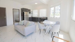 A modern living space with a sofa, dining table, chairs, and a kitchen area. - Close To The Beach Apt. 71Di.203 (San Juan)