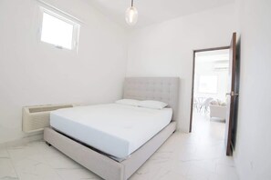 Un dormitorio con cama, ventana, puerta y radiador.