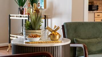 A dining area with a round table, chairs, a potted plant, and a small bowl of snacks.