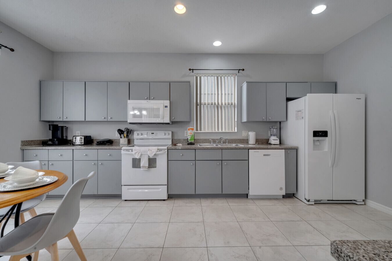 A modern kitchen with grey cabinets, a white stove, a microwave, a refrigerator, and a sink.