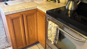 A kitchen with wooden cabinets, a stainless steel stove, and a tiled countertop.