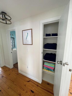 A hallway with wooden flooring, a white door with a silver handle, and a framed picture on the wall. - Peaceful lake front home with amazing views. (Middlesex)