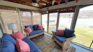 Una habitación con un sofá azul, un sillón de mimbre y una alfombra estampada.