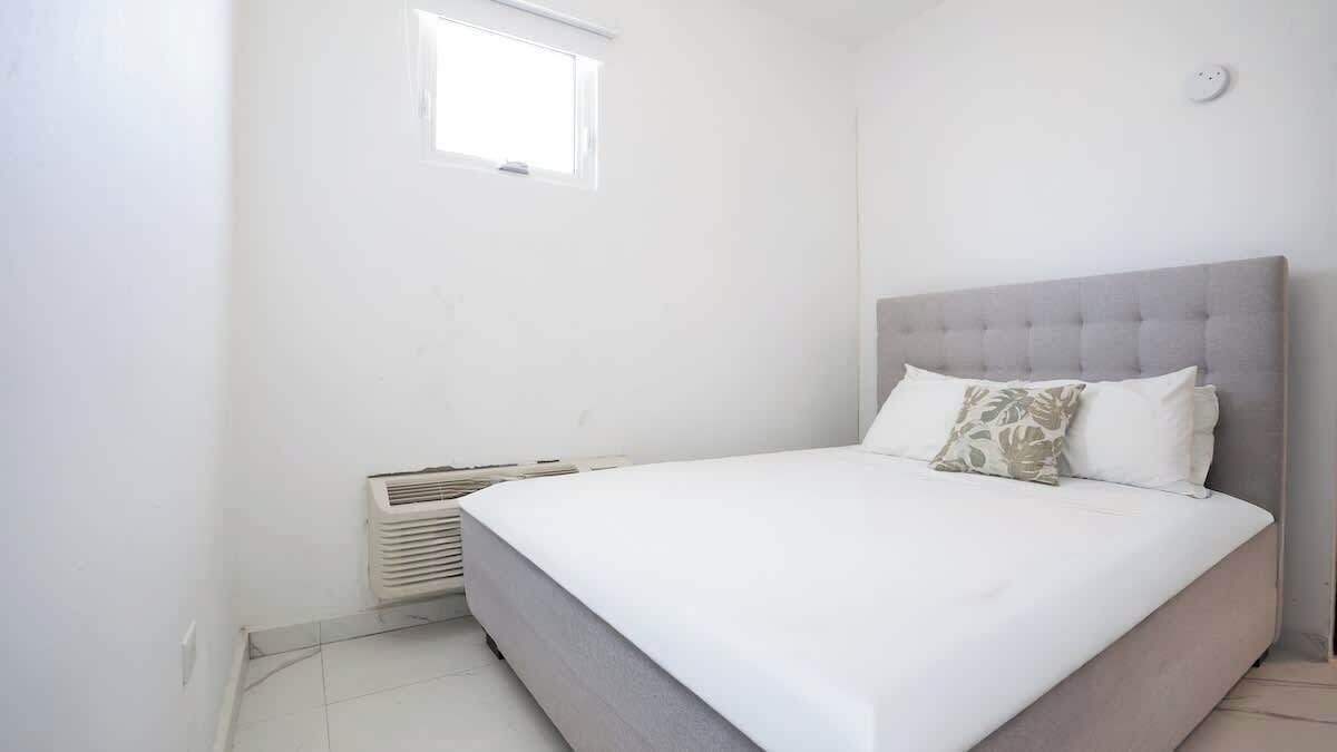 Un dormitorio con cama, ventana y aire acondicionado instalado en la pared.